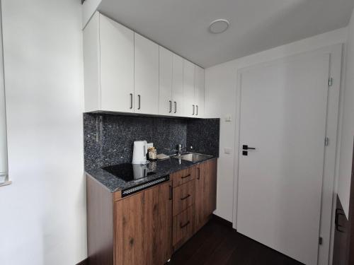 a kitchen with white cabinets and a sink at Inga Vacation House in Druskininkai