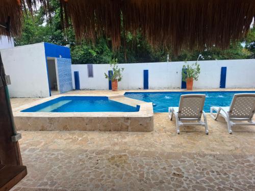 a swimming pool with two chairs and a table at Finca Villa Gabriela 