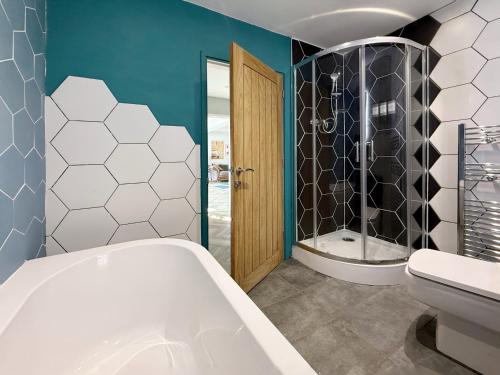 a bathroom with a tub and a toilet and a shower at Historic Hampshire Cottage with Private Putting Green in Eversley