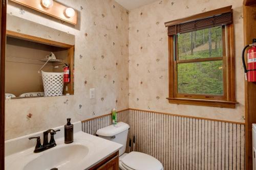 a bathroom with a sink and a toilet and a window at Elk Ridge Retreat -Hot Tub- Firepit-Fireplace in Maggie Valley