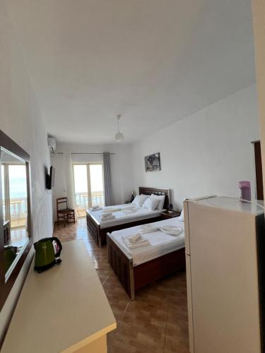 a hotel room with two beds and a refrigerator at Rock Star-Pllakat in Sarandë