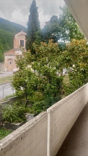 a retaining wall with trees and a house in the background at Appartamento Giacomo Leopardi in Piobbico