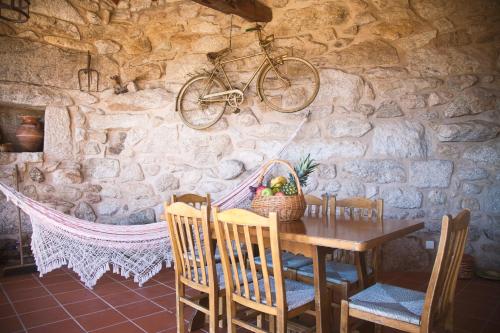 a table and chairs with a bike hanging on a stone wall at Casa De Santo Andre in Monção