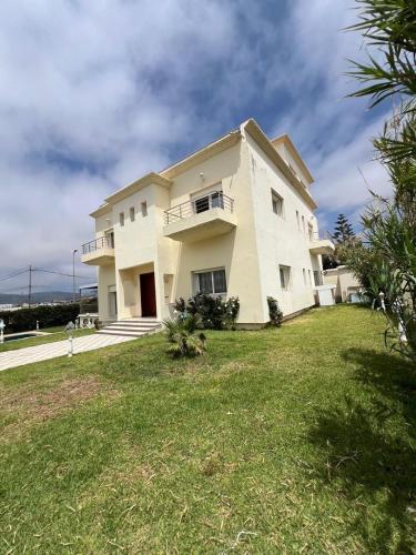 a large white house with a grass yard at Villa Belle Rive Estate in Oulad Akkou