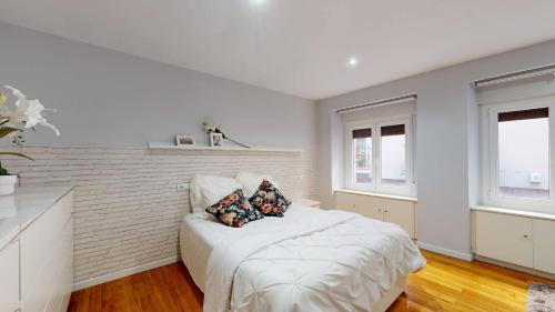 a white bedroom with a bed and two pillows at Apartamento Albizuri in Bilbao