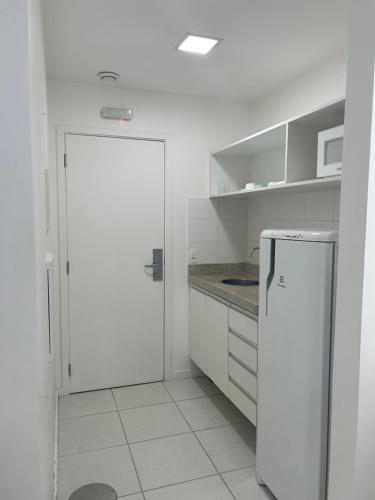 a white kitchen with a refrigerator and a microwave at Fusion e Vision Flats in Brasilia
