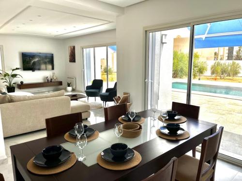 a dining room with a table and a living room at Villa Olivia in El Guecheïne