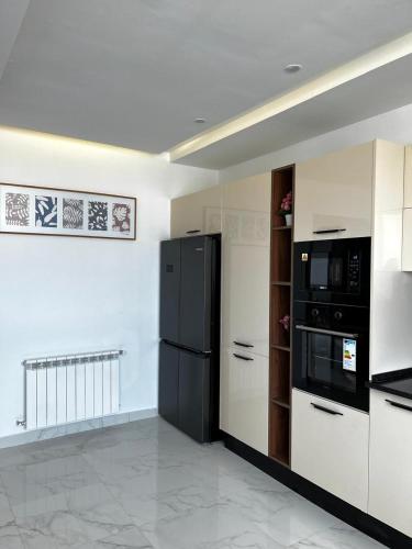 a kitchen with black appliances and white cabinets at Villa Olivia in El Guecheïne