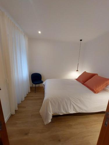 a bedroom with a white bed and a blue chair at Cottage - A Casa da Avó in São Vicente