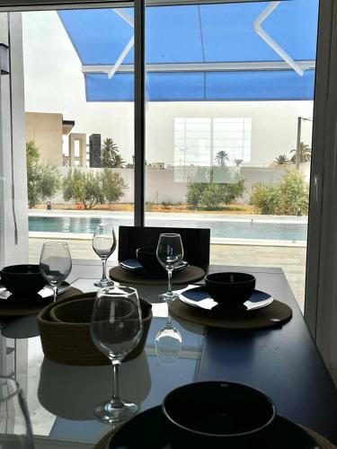 a dining table with wine glasses and a view of a pool at Villa Olivia in El Guecheïne
