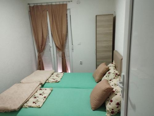 two twin beds in a room with a window at APARTMANI MARIJA in Čanj