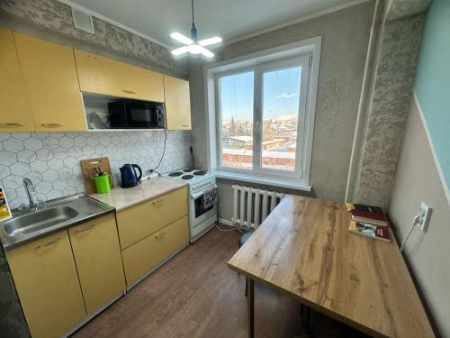 een kleine keuken met een houten tafel en een raam bij LuxHome на УК in Öskemen