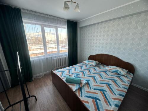 een slaapkamer met een bed en een groot raam bij LuxHome на УК in Öskemen