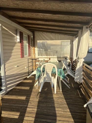 une terrasse couverte avec 2 chaises et une table. dans l'établissement La Carabasse 4 étoiles Mobilhome 6 personnes, 3 chambres tout confort, à Vias