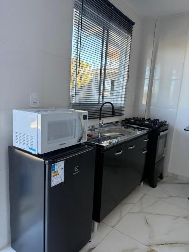 a kitchen with a microwave on top of a refrigerator at Pousada Vista da Serra, há 3min do Hospital Angelina Caron in Campina Grande do Sul