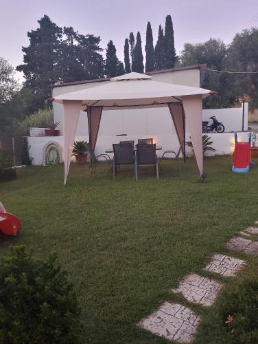 a white gazebo with chairs and a table in a yard at Notoshouse in Nótos