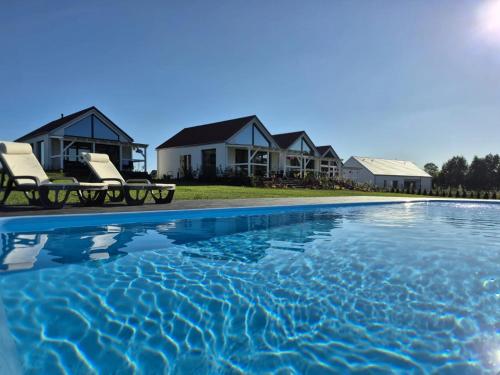 a villa with a swimming pool in front of a house at Osada Kalwa in Tylkowo
