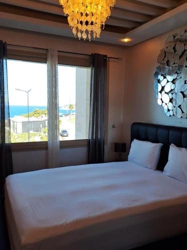 une chambre avec un grand lit avec une grande fenêtre dans l'établissement Séjour Prestige Vue Mer, Jacuzzi, Piscine, à Oulad Akkou