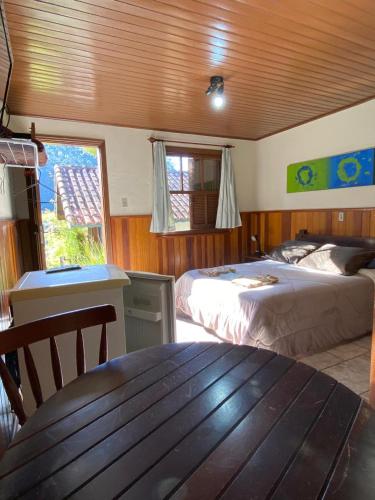 a bedroom with two beds and a table in a room at Chalés 4 Estações in Monte Verde