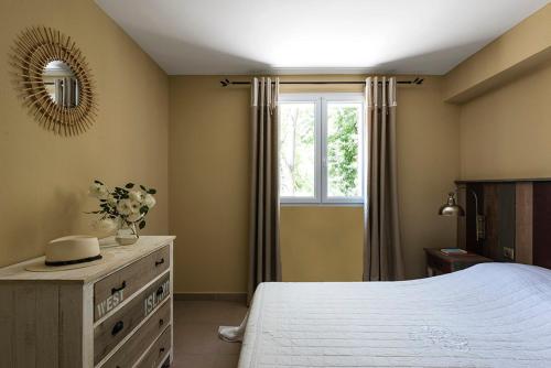 a bedroom with a bed with a dresser and a window at Les Jardins de la Mer in Grimaud