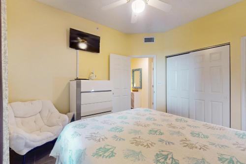 a bedroom with a bed and a chair and a door at The Dunes 704 in Gulf Shores