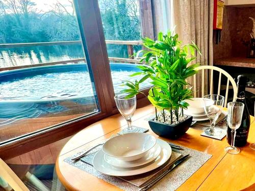 a wooden table with plates and glasses and a plant on it at Holly Lodge 12 Hot Tub in York