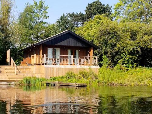 a cabin by a pond with a house at Holly Lodge 12 Hot Tub in York