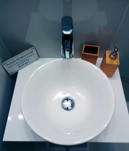 a white bathroom sink with aaucet and other items on a counter at Cloud9Rest & Fly in Koropíon