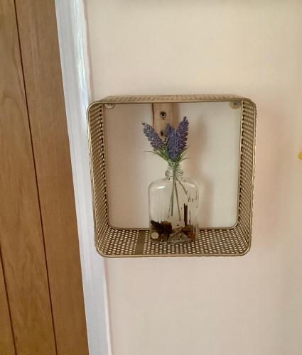 a mirror with a vase with purple flowers in it at Lorton Villa with a Log Burner in Saint Helens