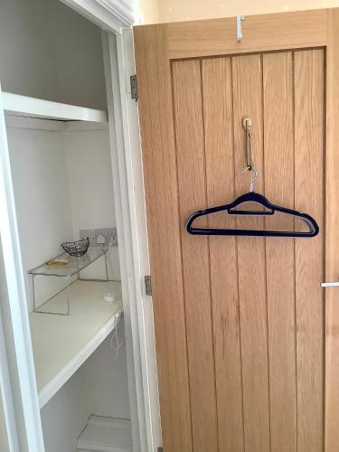 a closet with a wooden door with a hanger on it at Lorton Villa with a Log Burner in Saint Helens