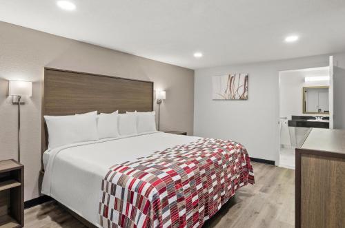 a bedroom with a large bed with a red and white blanket at Red Roof Inn Wytheville in Wytheville