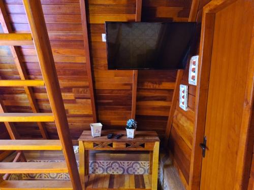 una habitación pequeña con un televisor y una mesa en Recanto sol maior - Chalé Jasmin, en Sapucaí-Mirim