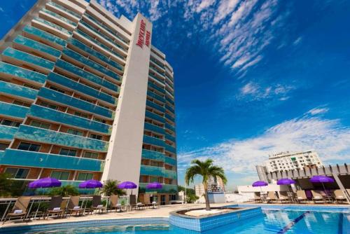 a hotel with a swimming pool in front of a building at Apê Central e Funcional in Nova Iguaçu
