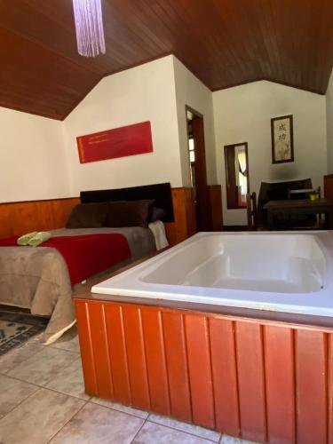 a large bath tub in a room with a bed at Chalés 4 Estações in Monte Verde