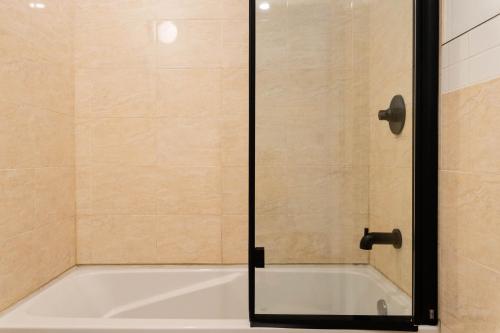 a bath tub with a glass shower door at Maison Rasco by Luxury In Transit in Montréal