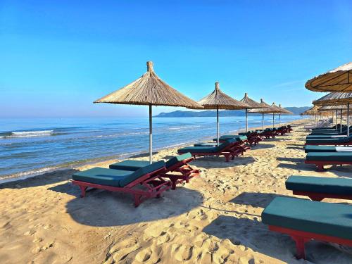 a row of beach chairs and umbrellas on a beach at White Moon Apartment 302 in Lalzit Bay