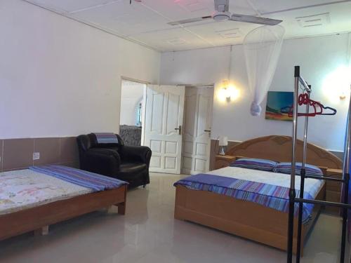 a bedroom with two beds and a chair in it at Sleeps8- Private Secure Parking- Garden- AirCon in Adeja