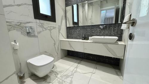 a bathroom with a white toilet and a sink at Modern 3 bedroom villa with pool in Paphos City