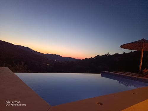 a swimming pool with a sunset in the background at Celini villa Tinos in Krokos