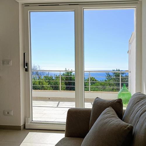 a living room with a couch in front of a sliding glass door at Living Castro Apartments in Castro di Lecce