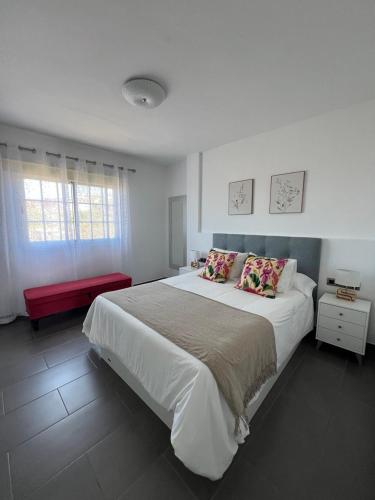 a bedroom with a large bed and a red bench at Apartamento Celma in Adeje