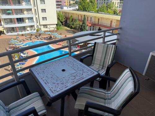 a table and chairs on a balcony with a pool at Central Plaza Apartment in Sunny Beach