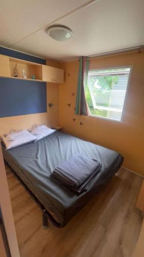 un petit lit dans une chambre avec une fenêtre dans l'établissement Camping Tohapi Coeur de Vendée, à La Boissière-de-Montaigu