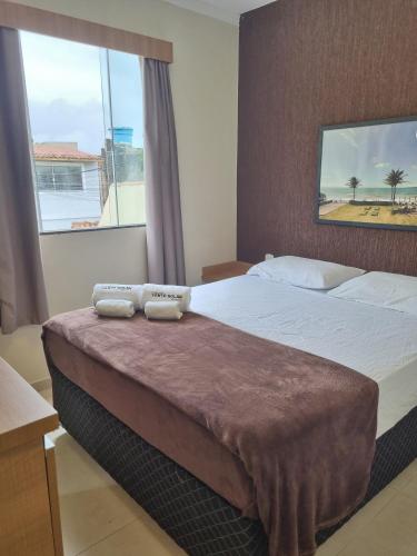 a bedroom with a large bed with a large window at Suites Vento Solar Buzios in Búzios