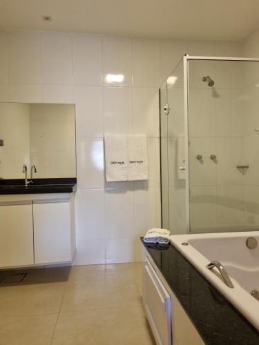 a bathroom with a tub and a shower and a sink at Suites Vento Solar Buzios in Búzios
