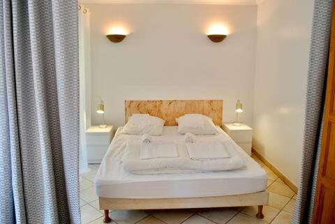 a white bed in a room with two night stands at Grand Hotel Des Bains & Villas des Bains in Vals-les-Bains