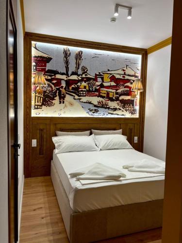 a bedroom with a bed with a painting on the wall at Tomas Inn in Pogradec