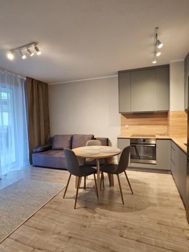 a kitchen and living room with a table and chairs at Apartament Lazurowy Olsztyn in Olsztyn