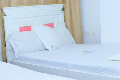 a white bed with two pillows on top of it at Parklands arena in Nairobi