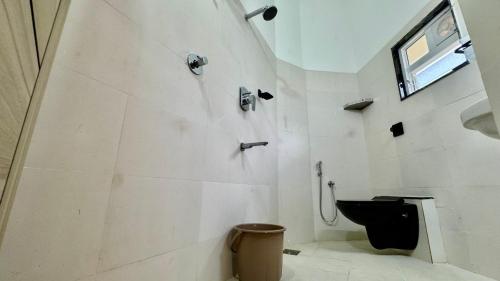 a bathroom with a black toilet and a window at Casa Nada Beach Villa in Udupi